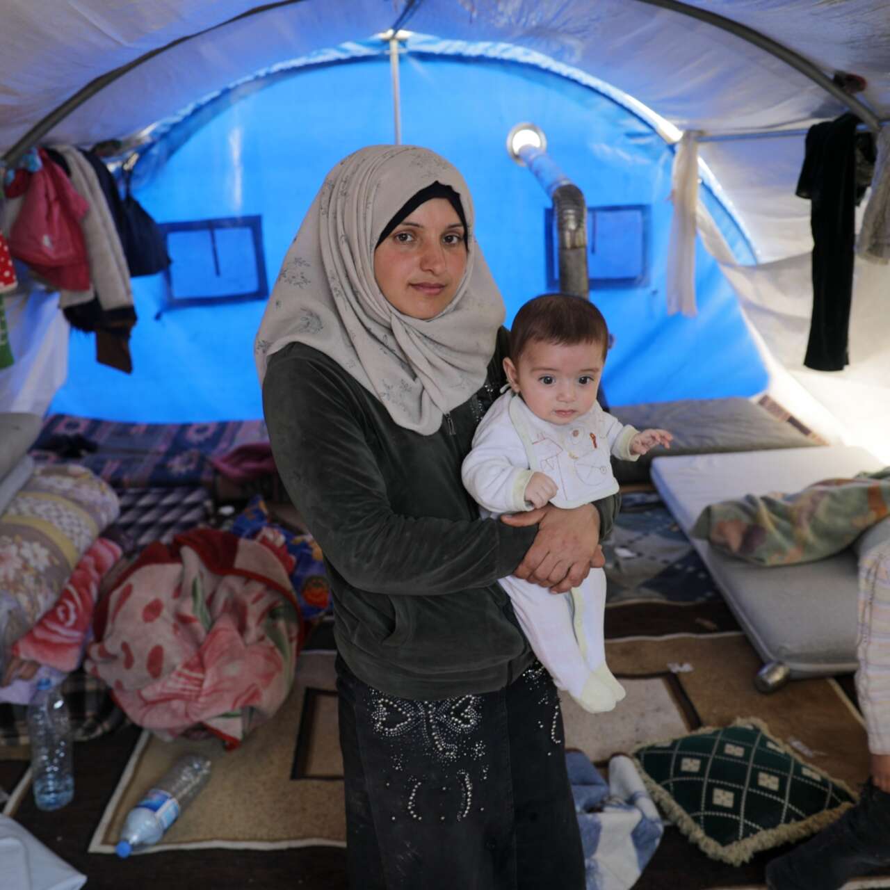 A family in Syria poses for a photo in their makeshift shelter in a refugee camp.