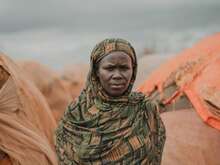 A woman poses solemnly for a photo outside of a makeshift shelter in Somalia.