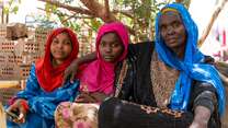 A mother and two daughters stare solemnly into the camera while posing for a portrait.