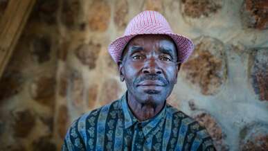 A man wears a red hat and solemnly stares into the camera for a portrait.