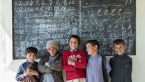 A group of boys smile and pose for a photo at their school in Paksistan.