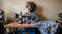 A woman, Domitila Kaliya, sewing dresses in her shared workspace in Kampala, Uganda