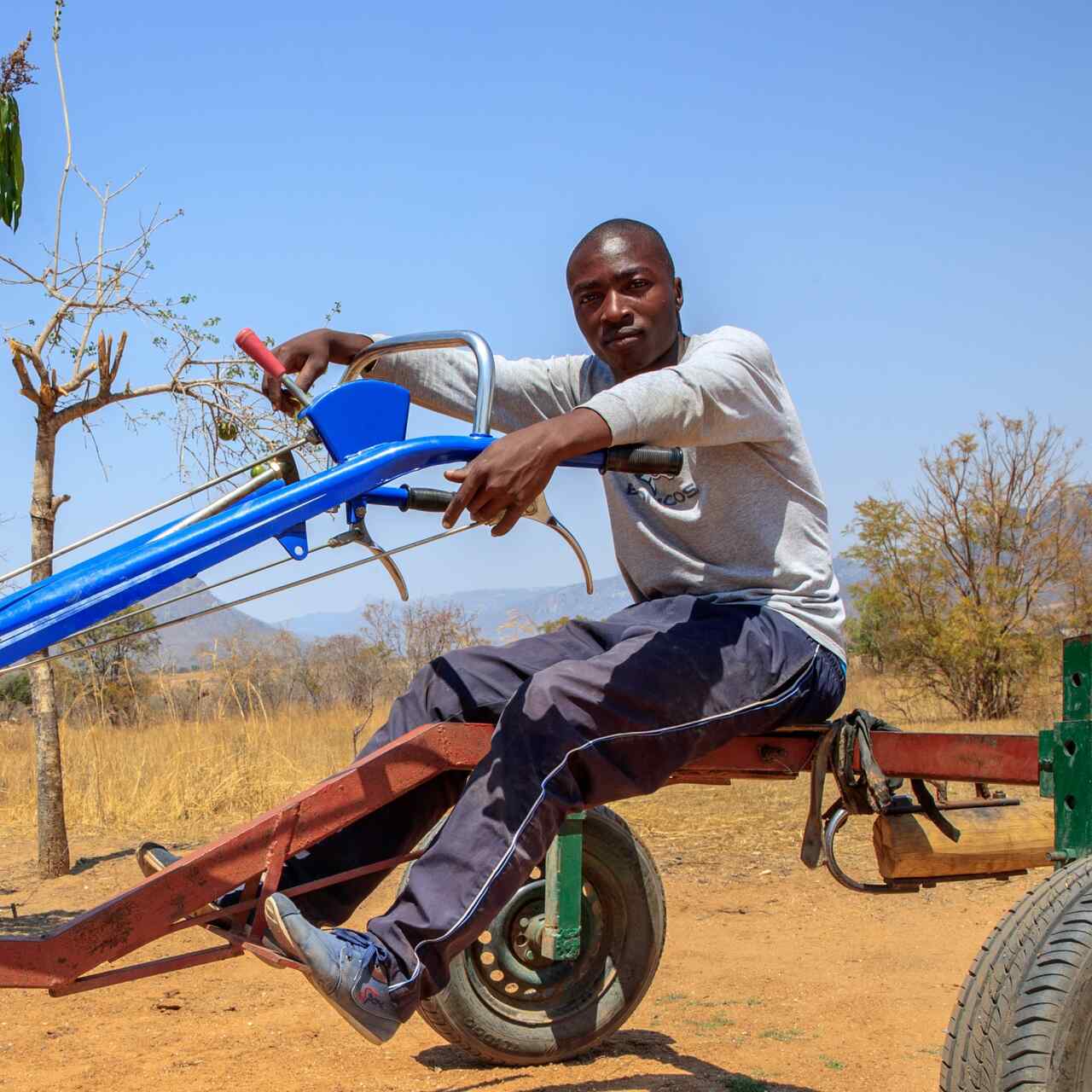 A man in Zimbabwe sits atop a piece of farming machinery.