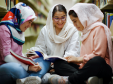 Three women in a library reading books together.