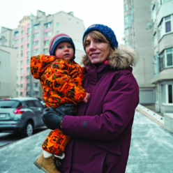 A mother outside in winter holding her child while looking off into the distance.