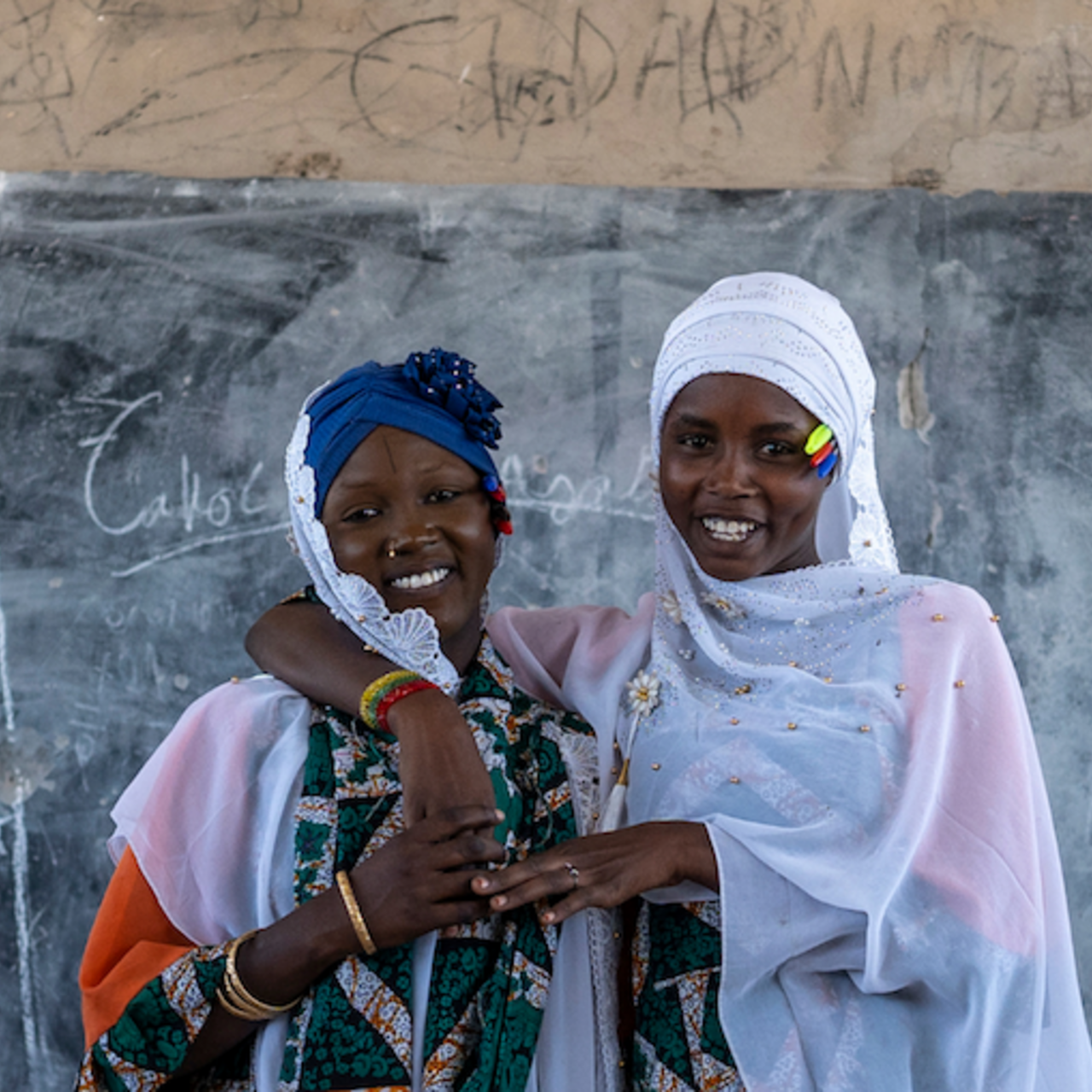 Two women in scarves looking at the camera and smiling