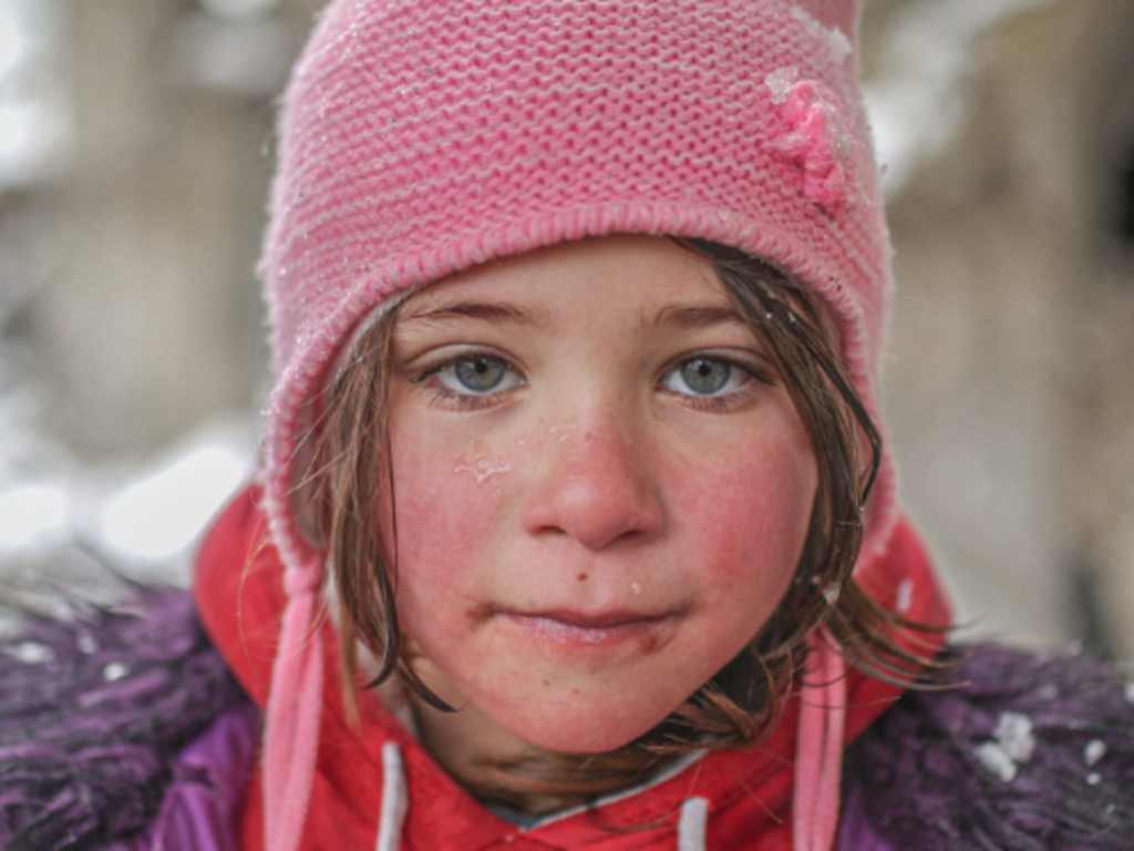 A girl wearing a pink hat in snow.